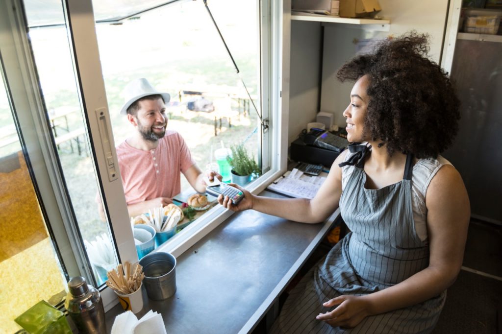 Man purchasing a pastry from a woman working in a food truck